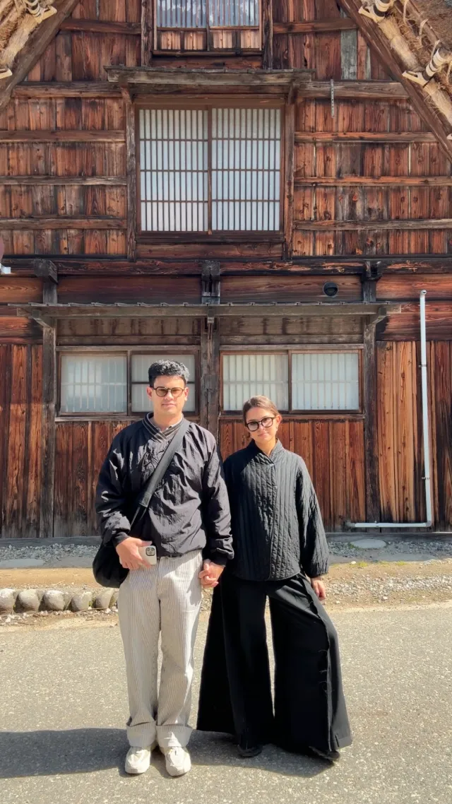 Two people standing in front of a traditional timber house